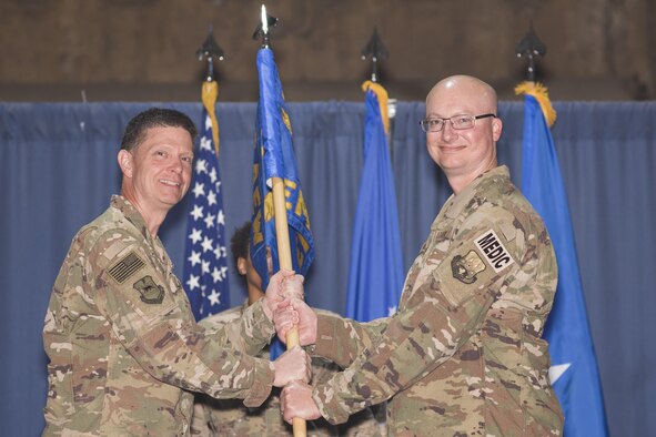 Brig. Gen. Kyle W. Robinson, 332nd Air Expeditionary Wing commander, left, passes the guidon to Col. Joseph V. Hale, during the 332nd Expeditionary Medical Group change of command ceremony June 3, 2017, in Southwest Asia. The passing of a guidon symbolizes a unit’s transfer of command. (U.S. Air Force photo/Senior Airman Damon Kasberg)