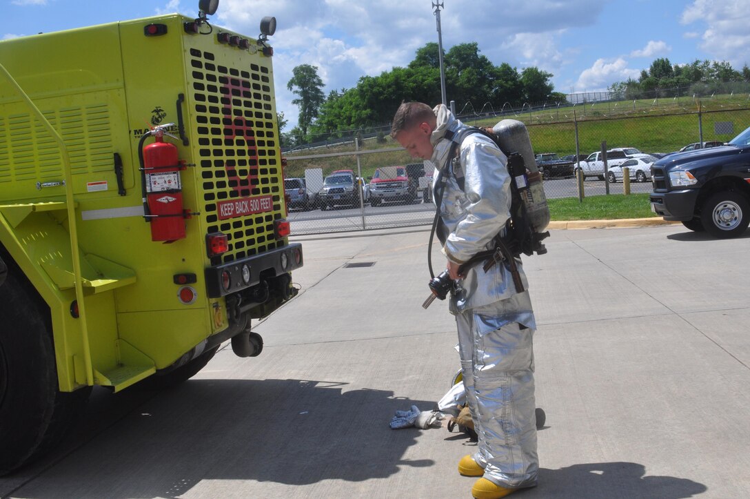 A Marine firefighter at Marine Corps Airfield (MCAF), demonstrates how to put on his specialized fire gear, which he has to put on in less than two minutes. The spouses were invited to time him.