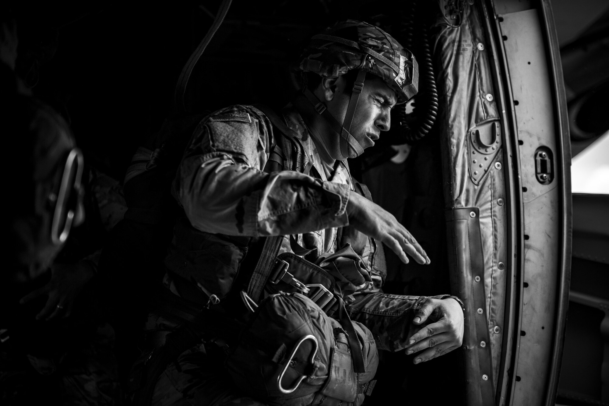 A U.S. Army soldier braces against the wind from the open side door of a U.S. Air Force C-130J Super Hercules assigned to the 37th Airlift Squadron at Ramstein Air Base, Germany, before jumping out near Sainte-Mere-Eglise, France, June 4, 2017. This event commemorates the 73rd anniversary of D-Day, the largest multinational amphibious landing and operational military airdrop in history, and highlights the U.S.' steadfast commitment to European allies and partners. Overall, approximately 400 U.S. service members from units in Europe and the U.S. are participating in ceremonial D-Day 73 events from May 31-June 7, 2017. (U.S. Air Force photo by Senior Airman Devin Boyer)