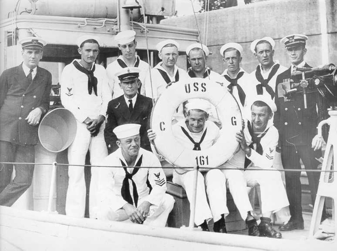 Coast Guard Patrol Force for the Albany, NY, Regatta, 1929.  The CG-161, commanded by Boatswain Herbert Mathews, was detailed from Section Base Two.  ENS J. H. Reeder was designated as officer in charge of the patrol force.  Left to right, standing: Boatswain (T) Herbert Mathews; BM2 W. F. Robinson; MoMM1 C. G. Mitchell; BM1 C. Bonde; MoMM1 G. Hansen; SEA1 J. Gordon; BM1 V. Thompson; ENS J.H. Reeder.  Framed by the cork ring is MoMM1 W. Kelly; on his left is MoMM1 N. Ward & MoMM1 W. Belser.  The CPO in the center is CBM Mate Le Walsh.