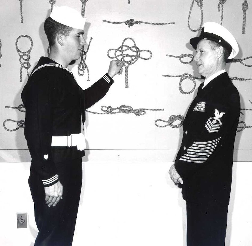 SN Larry M. McBreen (left) in a friendly discussion with QMC John Smith (right) regarding seamanship and knot tying.  Smith was a 33-year veteran of the Coast Guard.   
Both are in Class A Blues; photo dated 25 February 1959; photo number 13CGD-022059-02.
