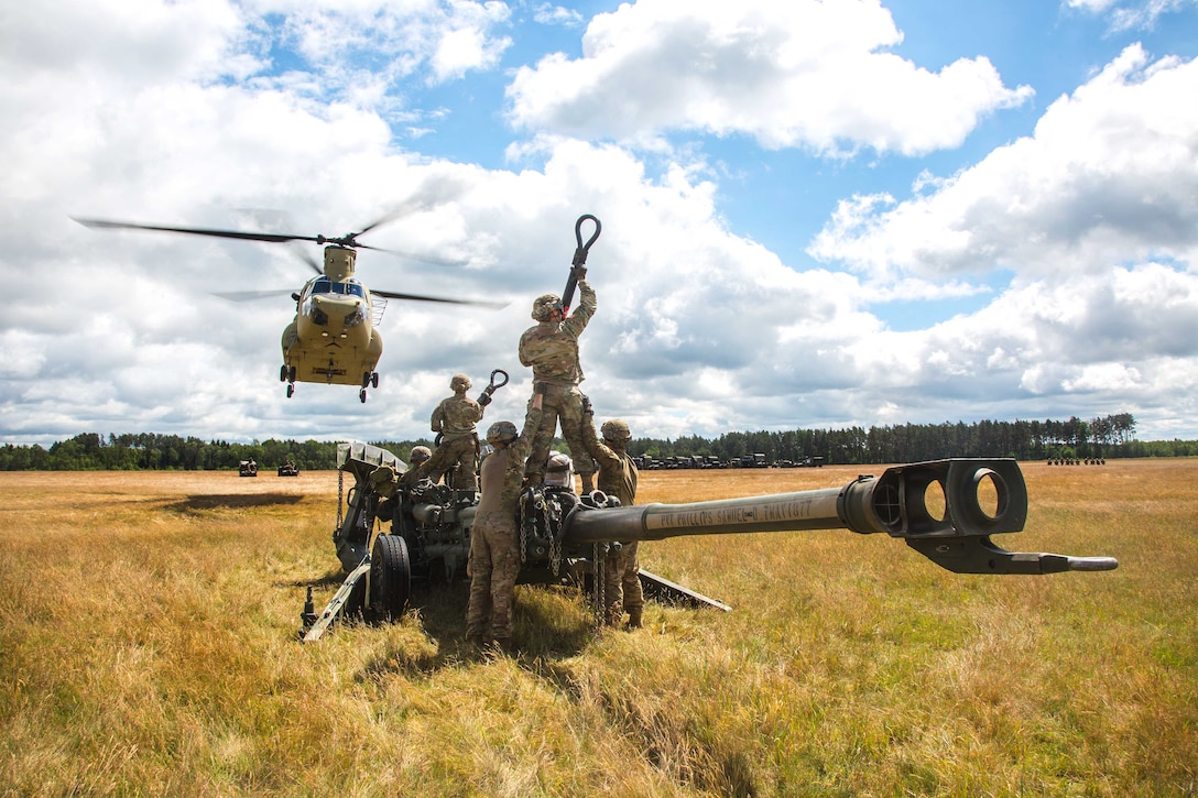 An Army CH-47 Chinook helicopter approaches as solders prepare to attach an M777A2 Howitzer gun during a slingload and air assault training as part of exercise Saber Strike 2017, at Bemowo Piskie Training Area near Orzysz, Poland, June 7, 2017. The soldiers are assigned to Bulldog Battery, 2nd Squadron, 2nd Cavalry Regiment. The helicopter crew is assigned to the 10th Mountain Combat Aviation Brigade. Saber Strike17 is a U.S. Army Europe-led multinational combined forces exercise conducted annually to enhance the NATO alliance throughout the Baltic region and Poland. Army photo by Spc. Stefan English