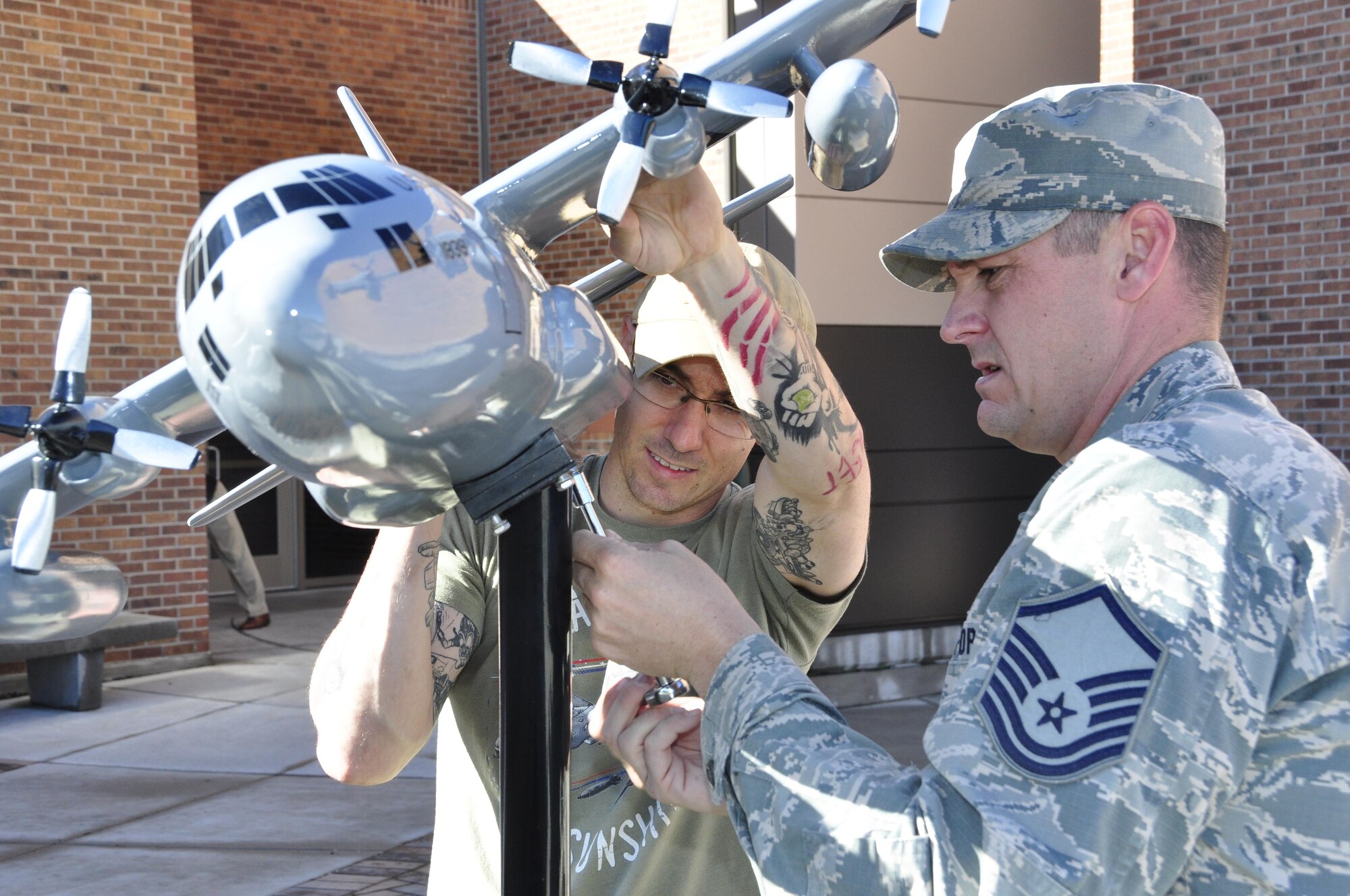 Tech. Sgt. Ryan Goode and Master Sgt. Shane Sturgeon, both 302nd Maintenance Squadron aircraft maintenance technicians secure a newly refurbished model C-130 Hercules to the display stand of the SUMIT 38 memorial outside Building 890 at Peterson Air Force Base, Colo., May 22, 2017. The display, which was destroyed by hail in July 2016, memorializes the loss of six Reserve Citizen Airmen assigned to the 302nd Airlift Wing who perished as a result of a C-130 crash that occurred May 13, 1995, near Boise, Idaho. “It was an honor for us to repair the memorial,” said Goode. “It was a shame to see it damaged the way it was.”  (U.S. Air Force photo/Staff Sgt. Frank Casciotta) 