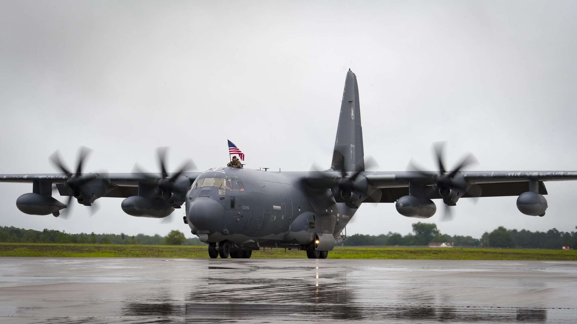 An Airman holds an American flag as a HC-130J Combat King II taxis on the flightline during a redeployment, June 6, 2017, at Moody Air Force Base, Ga. The 41st and 71st Rescue Squadrons were recently deployed to Southwest Asia where they provided combat search and rescue capabilities in support of Operation Inherent Resolve. (U.S. Air Force photo by Airman 1st Class Lauren M. Sprunk)
