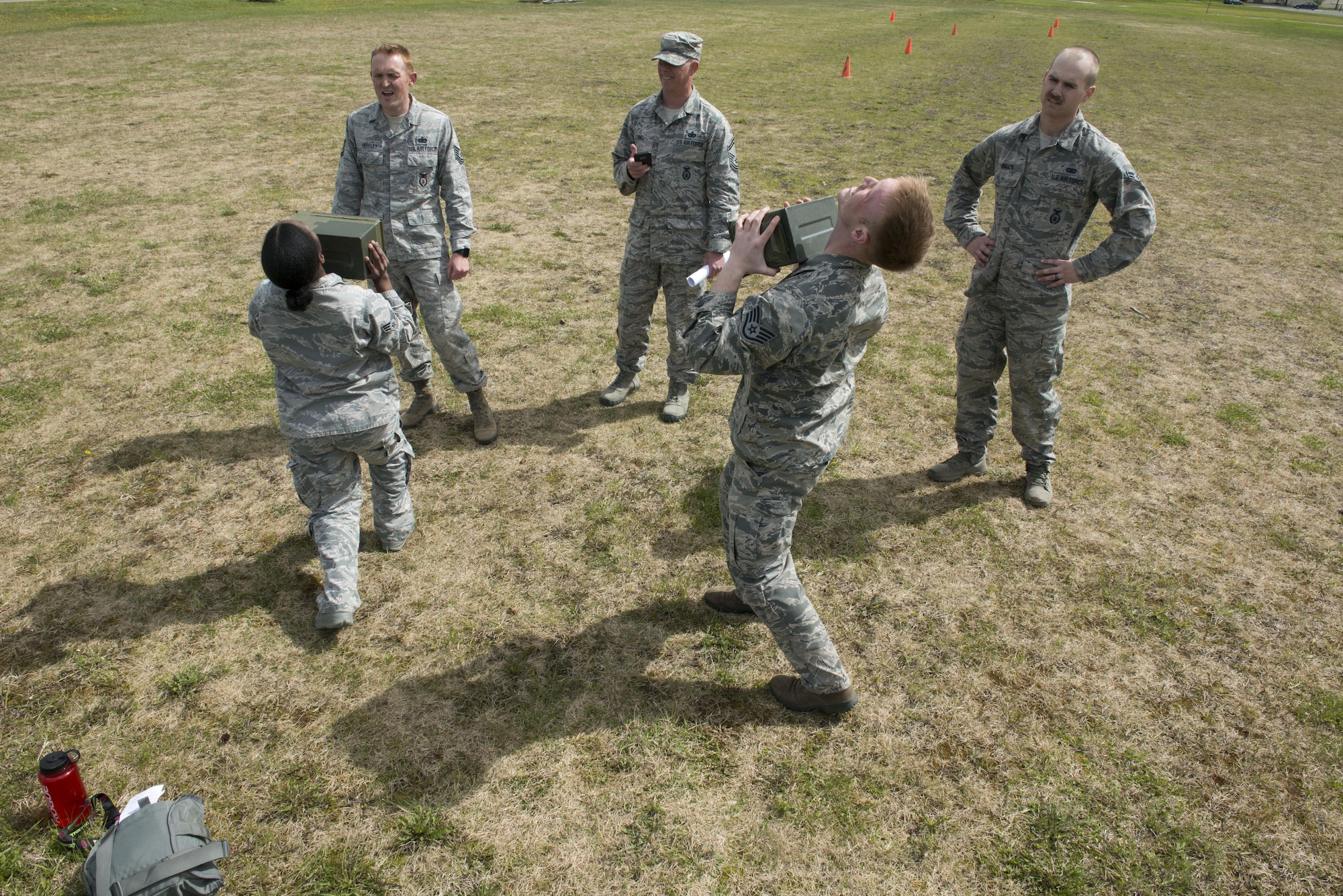 Senior Airman Michala Jordan and Air Force Staff Sgt. Christopher Bonham, both with the 673d Security Forces Squadron lift a full ammunition canister 91 times as quickly as possible while their teammates cheer them on outside the Elmendorf Fitness Center, May 25, 2017. The exercise was part of their 30-day training for the Pacific Air Forces Advanced Combat Skills Assessment. 