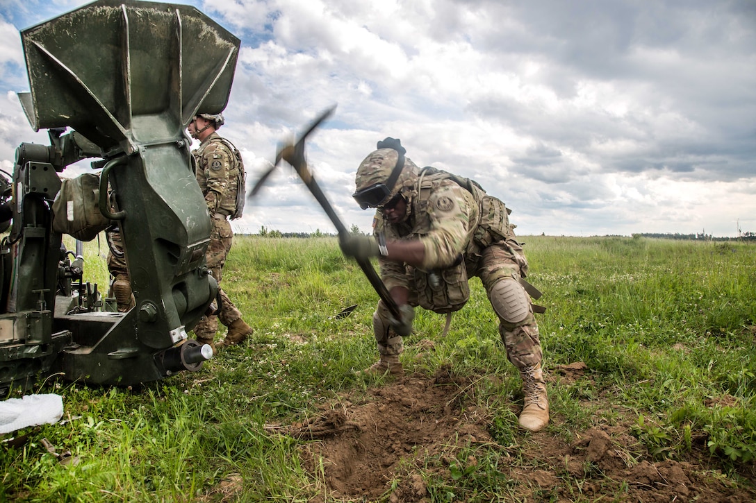 A soldier uses a pickaxe to dig a hole before emplacing an M777A2 Howitzer as part of exercise Saber Strike 2017, at Bemowo Piskie Training Area near Orzysz, Poland, June 7, 2017. Army photo by Spc. Stefan English