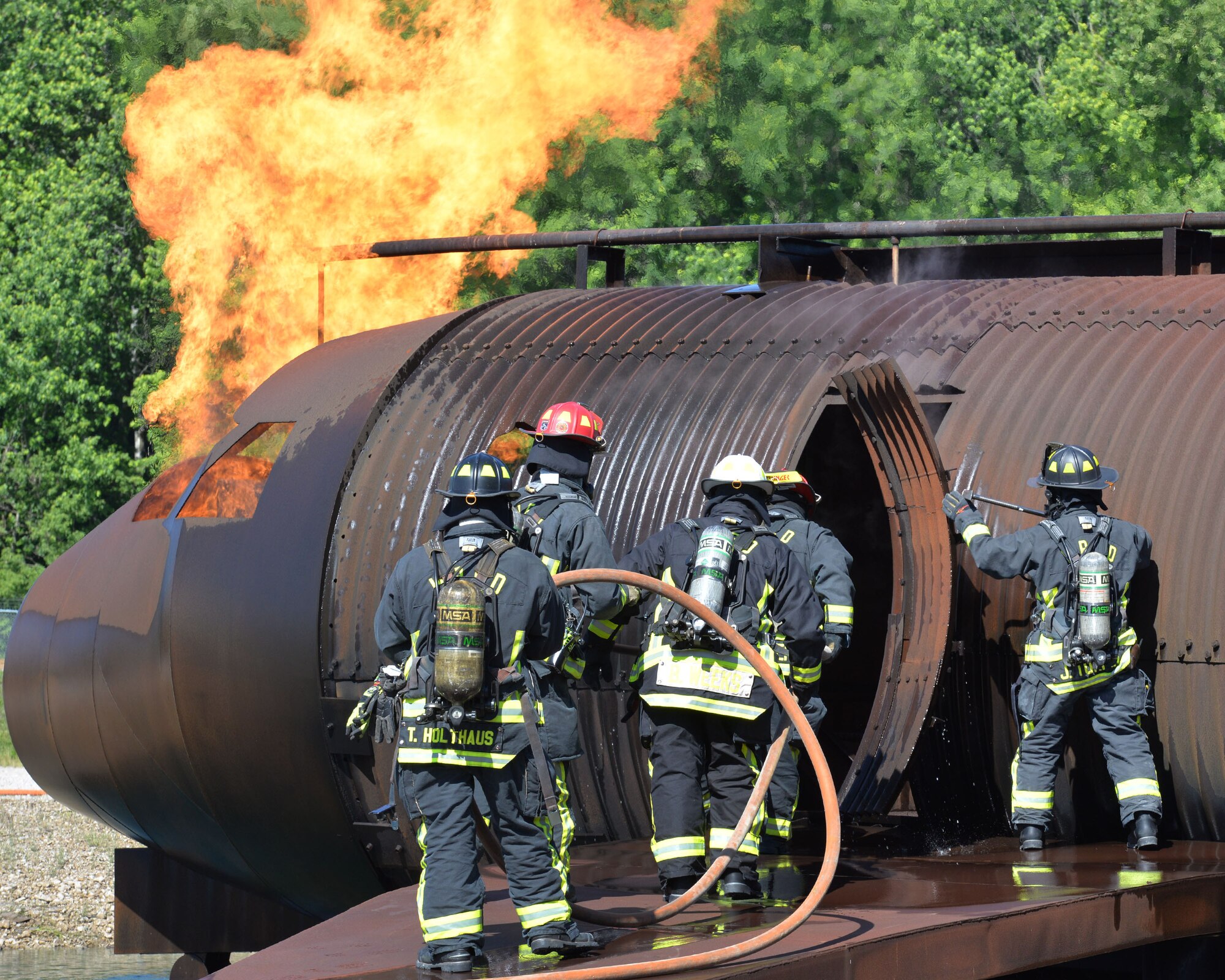 Firefighters, Anthony Holthaus, Matthew Smith, Bryan Weeks, Clark Deringer and Jason Turpin, all from the 788th Civil Engineer Squadron, perform aircraft live fire training as part of annual proficiency skill training for firefighters, at their training burn pit, May 30, 2017 at Wright-Patterson Air Force Base, Ohio. The crew demonstrated their ability to work as a team to position apparatus, deploy and advance hand lines, and extinguish aircraft and running fuel fires. (U.S. Air Force photo/Michelle Gigante)