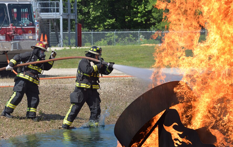 Firefighters, (left to right) Garry Hill and Chad Engman, from the 788th Civil Engineer Squadron, extinguish an aircraft fire as part of their annual proficiency skill training for firefighters, at Wright-Patterson Air Force Base, Ohio, May 30, 2017. The crew had to demonstrate their ability to work as a team to attack and extinguish two and three-dimensional fires, example—simulated fuel fire, pooling, spilling, running from the engines and on the ground. (U.S. Air Force photo/Michelle Gigante)