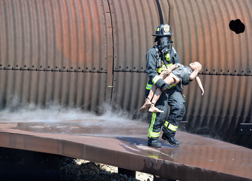 Richard Breitenstein 788th Civil Engineer Squadron firefighter, carries a mannequin from an aircraft after successfully putting out a fire inside their training burn pit, May 30, 2017 at Wright-Patterson Air Force Base, Ohio. Crews extinguished two different kinds of aircraft fires in addition to conducting searches for victims as part of their annual proficiency skill training for firefighters. (U.S. Air Force photo/Michelle Gigante) 