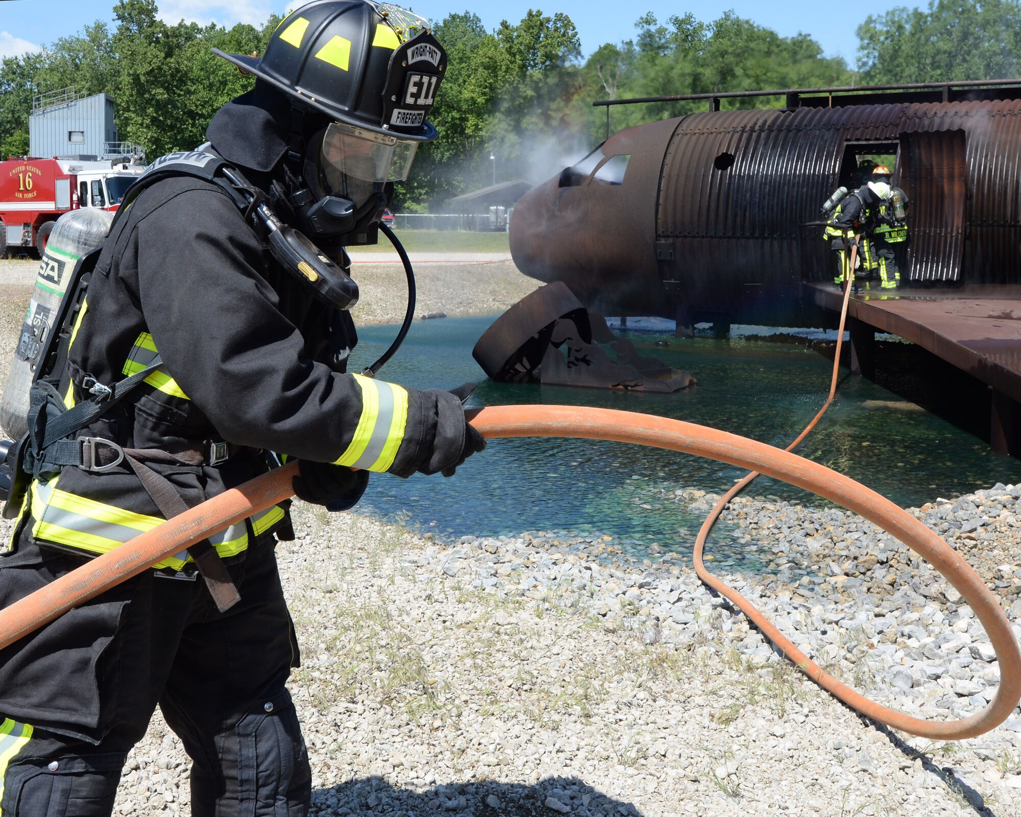 Davey Watson, 788th Civil Engineer Squadron firefighter, helps deploy the hose, during an aircraft live fire training as part of annual proficiency skill training for firefighters, May 30, 2017, at Wright-Patterson Air Force Base, Ohio. The crew had to demonstrate their ability to apply fire streams to a given area while operating the apparatus. (U.S. Air Force photo/Michelle Gigante)