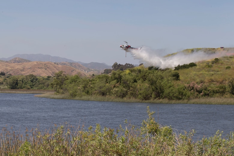 A CAL FIRE Bell 407 helicopter drops water on simulated fire area during the 2017 Wildland Firefighting Exercise (WLFFEX) at Lake O'Neill on Camp Pendleton, Calif., May 4, 2017. The WLFFEX is an annual training event to exercise the firefighting efforts by aviation and ground assests from Marine Corps Installations - West, Marine Corps Base, Camp Pendleton, 3rd Marine Air Wing, Navy Region South West, Third Fleet, CAL FIRE, and San Diego County Sheriff's Department. (U.S. Marine Corps photo by Cpl. Brandon Martinez)