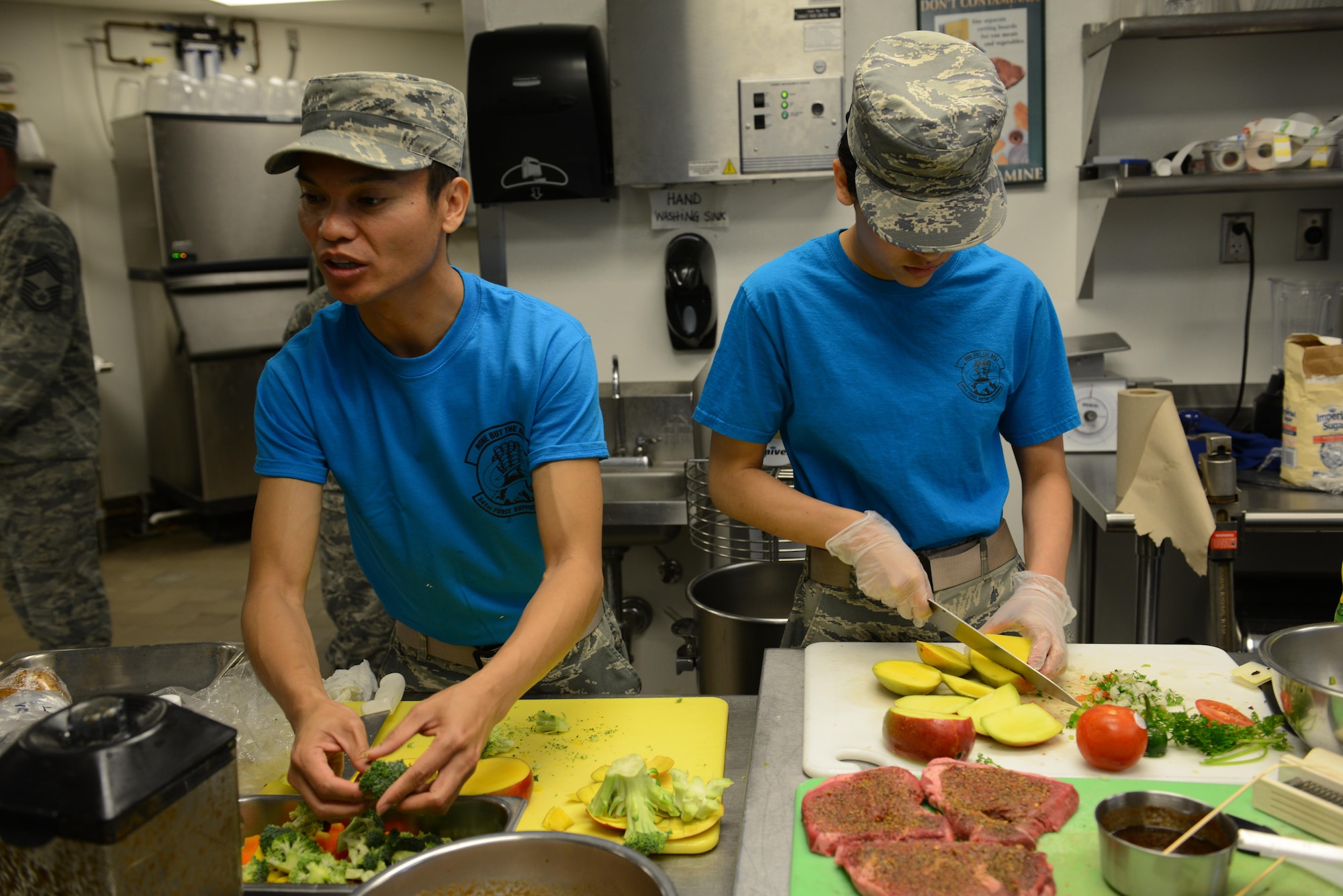 Airman 1st Class Nicki Agunos, 341st Force Support Squadron missile chef, left, checks on his sous chef while he prepares vegetables for sautéing June 7, 2017 at Malmstrom Air Force Base, Mont. Agunos and his partner Staff Sgt. Amber Sansone prepared a surf and turf themed meal complete with salad. (U.S. Air Force photo/Staff Sgt. Delia Marchick)