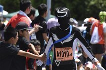 A participant in costume exchanges low-fives with children during the 33rd Annual Yokota Striders Ekiden Race at Yokota Air Base, Japan, June 4, 2017. The races, which consisted of a 2K Kids Run, 2K Family Run, 5K Race and the main Ekiden Race event, promoted friendship and physical fitness. (U.S. Air Force photo by Machiko Arita)