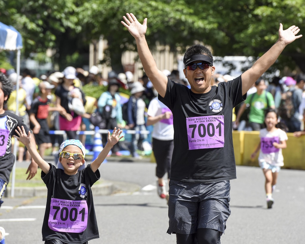 A father and daughter cross the finish line together with their hands up at the 2K Family Run during the 33rd Annual Yokota Striders Ekiden at Yokota Air Base, Japan, June 4, 2017. More than 5,000 runners participated in the event hosted by the Yokota Striders Running Club. (U.S. Air Force photo by Machiko Arita)