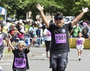 A father and daughter cross the finish line together with their hands up at the 2K Family Run during the 33rd Annual Yokota Striders Ekiden at Yokota Air Base, Japan, June 4, 2017. More than 5,000 runners participated in the event hosted by the Yokota Striders Running Club. (U.S. Air Force photo by Machiko Arita)