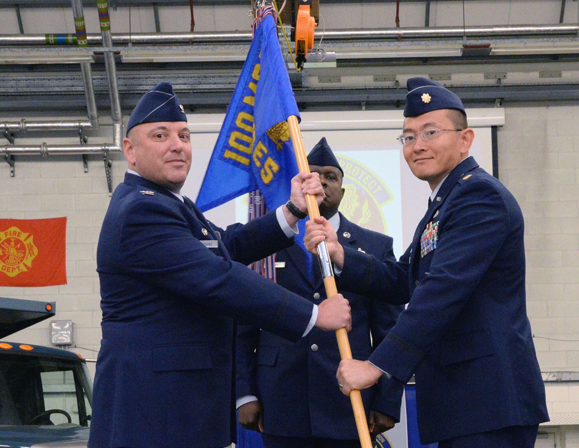 U.S. Air Force Col. Robert Hoskins, left, 100th Mission Support Group commander, passes the guidon to U.S. Air Force Maj. Robert Liu, new 100th Civil Engineer Squadron commander, June 6, 2017, during a change of command ceremony on RAF Mildenhall, England. The ceremony is a time-honored tradition in which one officer relinquishes command and passes it to another. (U.S. Air Force photo by Karen Abeyasekere)