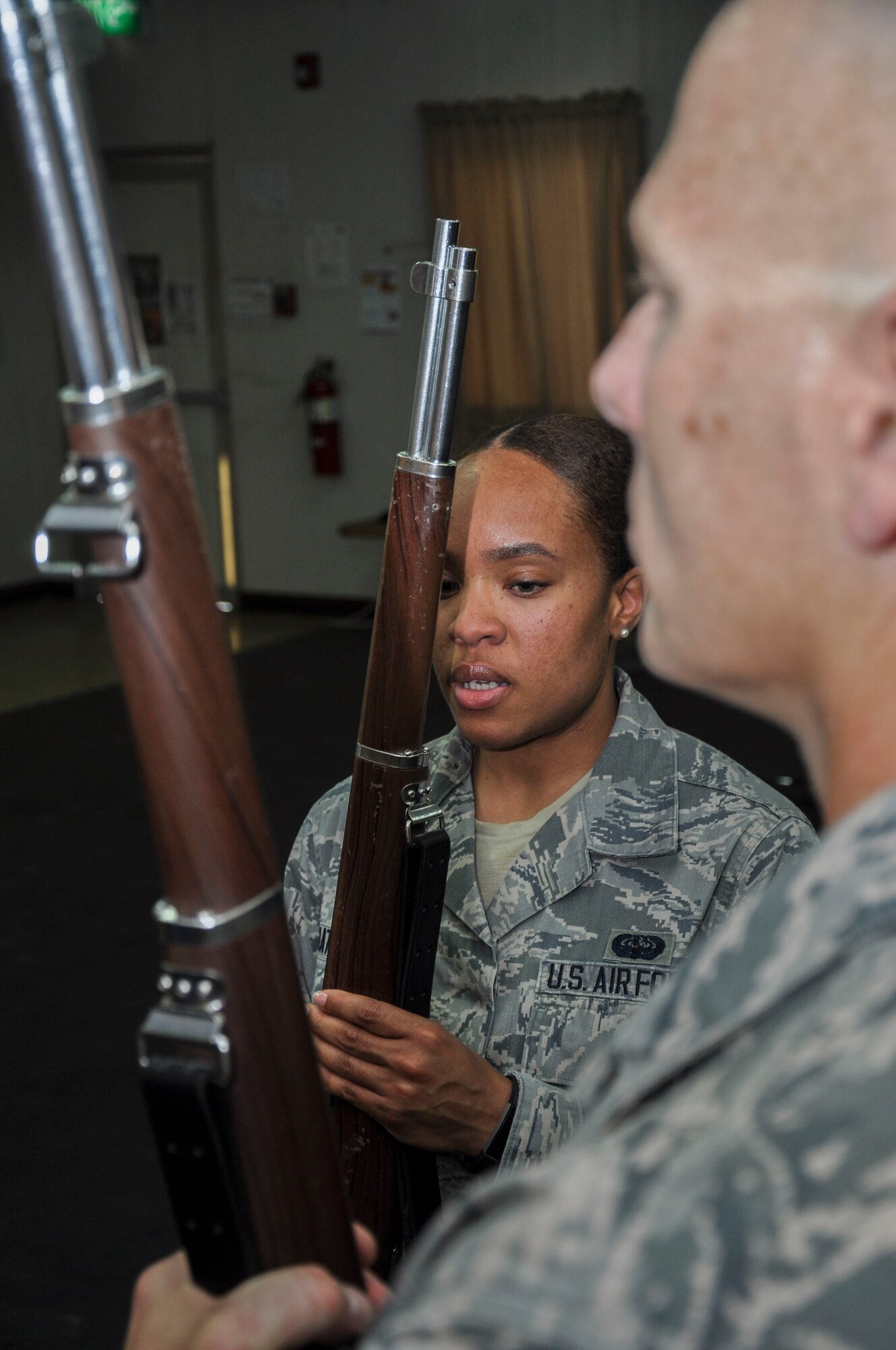 Senior Airman Dazzmin Mathews (left), ceremonial guardsman, demonstrates proper rifle maneuver technique to a teammate at a practice session Tuesday, May 30, 2017, at the base theater at an undisclosed location in Southwest Asia.  Airman Mathews is deployed from Nellis Air Force Base Nevada.