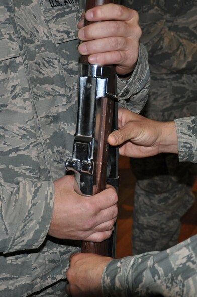 Staff Sgt. David Adolfo (right), honor guard trainer, makes a find adjustment to the angle at which a team member holds his rifle Tuesday, May 30, 2017, in the base theater at an undisclosed location in Southwest Asia. Honor guard movements are grounded on exacting precision and synchronization between each team member. (U.S. Air Force photo/Master Sgt. Eric M. Sharman)