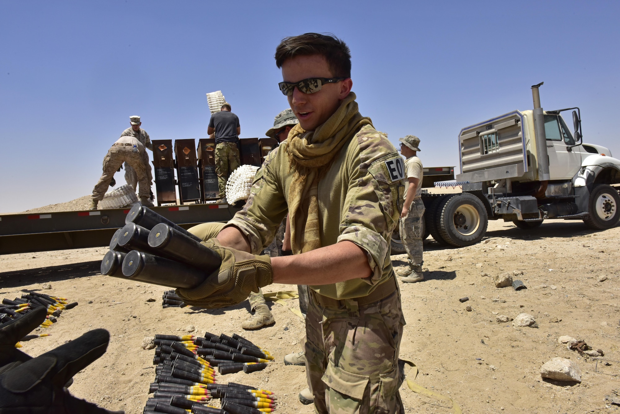 Senior Airman Kevin Oserguera, 407th Expeditionary Civil Engineer Squadron explosive ordnance disposal (EOD) technician, hands off munitions on a production line to unload a trailer during an explosive ordnance disposal (EOD) operation in Southwest Asia, June 6, 2017. Personnel from the 407th Expeditionary Civil Engineer Squadron EOD, U.S. Marine Corps Special Marine Air Ground Task Force EOD and Italian Air Force completed the task of disposing of more than 5,000 pieces of expired 30 mm rounds and aircraft decoy flares. EOD’s mission is to protect personnel, resources, and the environment from hazardous explosive ordnance, improvised explosive devices and weapons of mass destruction, which may include; incendiary, chemical, biological, radiological, and nuclear hazards.  They specialize in tools, techniques and personal protective equipment to detect or identify, monitor, evaluate, interrogate, mitigate, render safe, recover, and disposal operations on ordnance or devices delivered, placed, or made dangerous by any circumstances. (U.S. Air Force photo by Senior Airman Ramon A. Adelan)