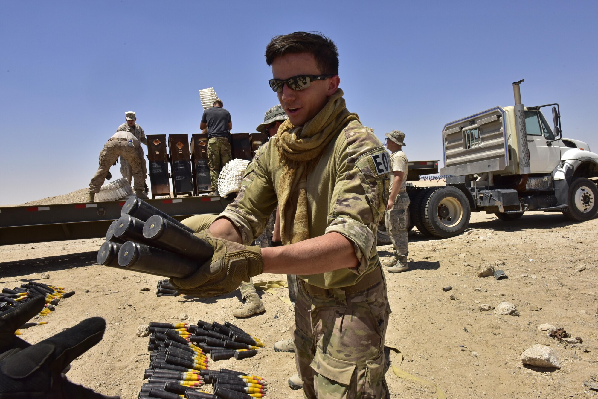 Senior Airman Kevin Oserguera, 407th Expeditionary Civil Engineer Squadron explosive ordnance disposal (EOD) technician, hands off munitions on a production line to unload a trailer during an explosive ordnance disposal (EOD) operation in Southwest Asia, June 6, 2017. Personnel from the 407th Expeditionary Civil Engineer Squadron EOD, U.S. Marine Corps Special Marine Air Ground Task Force EOD and Italian Air Force completed the task of disposing of more than 5,000 pieces of expired 30 mm rounds and aircraft decoy flares. EOD’s mission is to protect personnel, resources, and the environment from hazardous explosive ordnance, improvised explosive devices and weapons of mass destruction, which may include; incendiary, chemical, biological, radiological, and nuclear hazards.  They specialize in tools, techniques and personal protective equipment to detect or identify, monitor, evaluate, interrogate, mitigate, render safe, recover, and disposal operations on ordnance or devices delivered, placed, or made dangerous by any circumstances. (U.S. Air Force photo by Senior Airman Ramon A. Adelan)