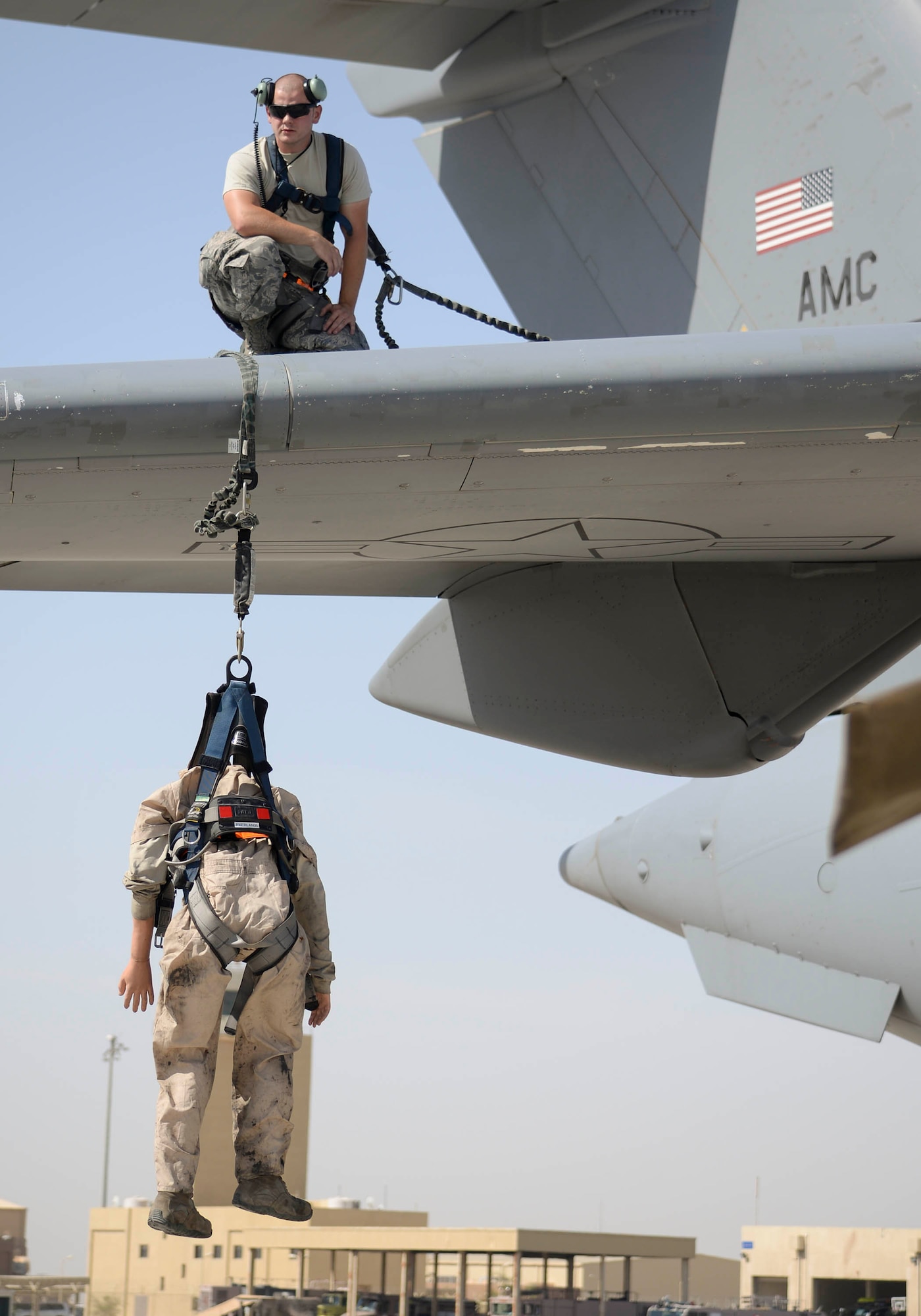 U.S. Air Force Airman 1st Class Jacob Trimble, guidance and control technician assigned to the 8th Expeditionary Air Mobility Squadron looks on from the wing of a C-17 Globemaster III as a training dummy hangs from the wing suspended by a fall restraint system simulating an accidental fall from the wing during an exercise at Al Udeid Air Base, Qatar, June 6, 2017. The fall protection exercise was conducted in support of Fall Protection Awareness Month and was designed to test the 8 EAMS’ fall protection rescue plan. (U.S. Air Force photo by Tech. Sgt. Bradly A. Schneider/Released)