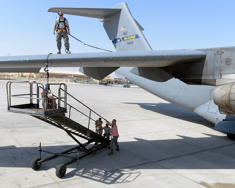 U.S. Air Force Airman 1st Class Jacob Trimble, guidance and control technician, looks on from the wing of a C-17 Globemaster III as Staff Sgts. Brett Rice, crew chief, left, Gerardo Pesebre, Jr., repair and reclamation crew chief, center, and Senior Airman Kyle Sherburne, communication and navigation technician, right, move the rescue stairs into place during a fall protection exercise at Al Udeid Air Base, Qatar, June 6, 2017. The fall protection exercise was conducted by the members of the 8th Expeditionary Air Mobility Squadron, in support of Fall Protection Awareness Month and was designed to test the 8 EAMS’ fall protection rescue plan. (U.S. Air Force photo by Tech. Sgt. Bradly A. Schneider/Released)