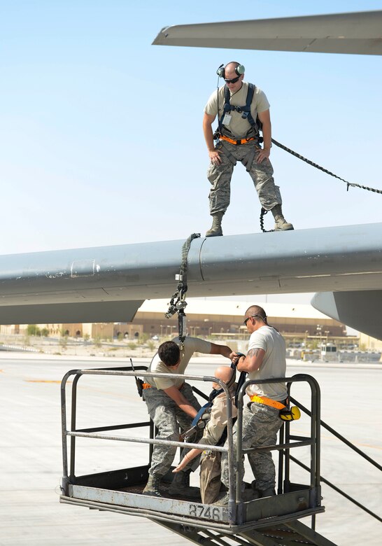 U.S. Air Force Airman 1st Class Jacob Trimble, guidance and control technician, looks on from the wing of a C-17 Globemaster III as Staff Sgts. Brett Rice, crew chief, left, and Gerardo Pesebre, Jr., repair and reclamation crew chief, “save” a training dummy from a fall restraint system during an exercise at Al Udeid Air Base, Qatar, June 6, 2017. The fall protection exercise was conducted by members of the 8th Expeditionary Air Mobility Squadron in support of Fall Protection Awareness Month and was designed to test the 8 EAMS’ fall protection rescue plan. (U.S. Air Force photo by Tech. Sgt. Bradly A. Schneider/Released)