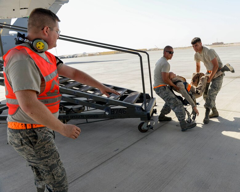U.S. Air Force Senior Airman Kyle Sherburne, communication and navigation technician, foreground, points out a safe place for Staff Sgts. Brett Rice, crew chief, right, and Gerardo Pesebre, Jr., repair and reclamation crew chief, to place the training dummy recently rescued from a fall restraint system during a fall protection exercise at Al Udeid Air Base, Qatar, June 6, 2017. The fall protection exercise was conducted by members of the 8th Expeditionary Air Mobility Squadron in support of Fall Protection Awareness Month and was designed to test the 8 EAMS’ fall protection rescue plan. (U.S. Air Force photo by Tech. Sgt. Bradly A. Schneider/Released)