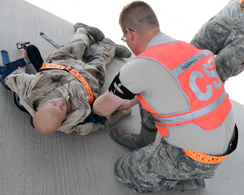 U.S. Air Force Senior Airman Kyle Sherburne, communication and navigation technician, assigned to the 8th Expeditionary Air Mobility Squadron, simulates checking vital signs on a training dummy recently removed from a fall restraint system during a fall protection exercise at Al Udeid Air Base, Qatar, June 6, 2017. The fall protection exercise was held in support of Fall Protection Awareness Month and was designed to test the 8 EAMS’ fall protection rescue plan. (U.S. Air Force photo by Tech. Sgt. Bradly A. Schneider/Released)
