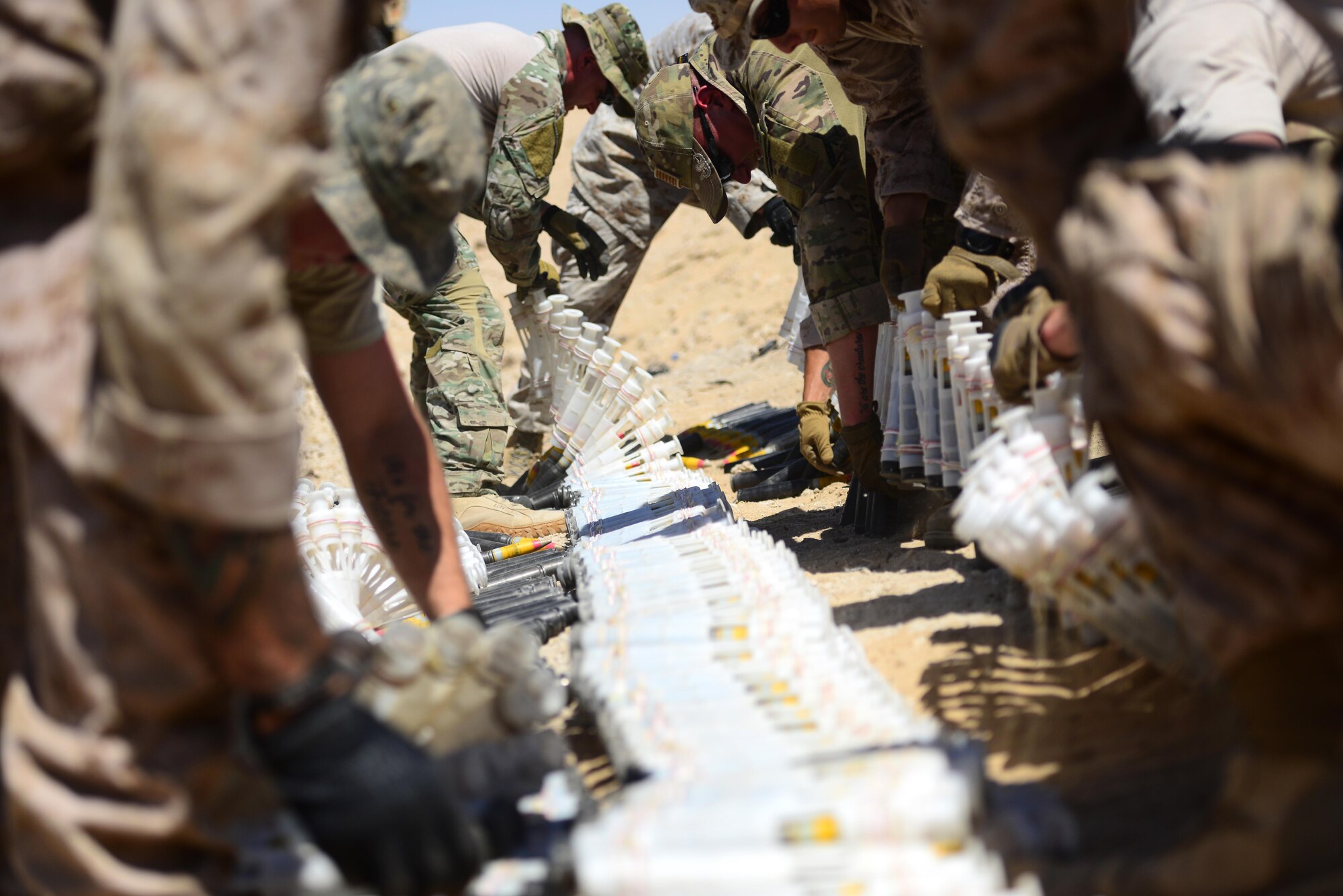 U.S. Air Force, U.S. Marine Corps and coalition partners assigned to the 407th Air Expeditionary Group prepare more than 5,000 pieces of unserviceable 30mm rounds and aircraft decoy flares for a coordinated detonation at the bomb range in Southwest Asia on June 6, 2017. Explosive ordnance disposal technicians are charged with locating, identifying, disarming, neutralizing, recovering, and disposing of hazardous explosives; conventional, chemical, biological, incendiary, and nuclear ordnance; and criminal or terrorist devices. (U.S. Air Force photo by Tech Sgt. Andy M. Kin)