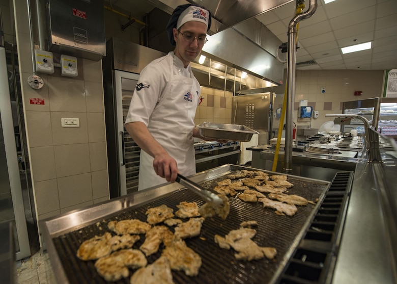 Airman Nathaniel Johnson, 31st Force Support Squadron food service apprentice, grills fresh chicken for lunch May 26, 2017, at Aviano Air Base, Italy. The La Dolce Vita, Aviano AB dining facility, has recently made improvements to provide healthier options and enhance the quality of food for Airmen and Soldiers. (U.S. Air Force photo by Senior Airman Cory W. Bush)