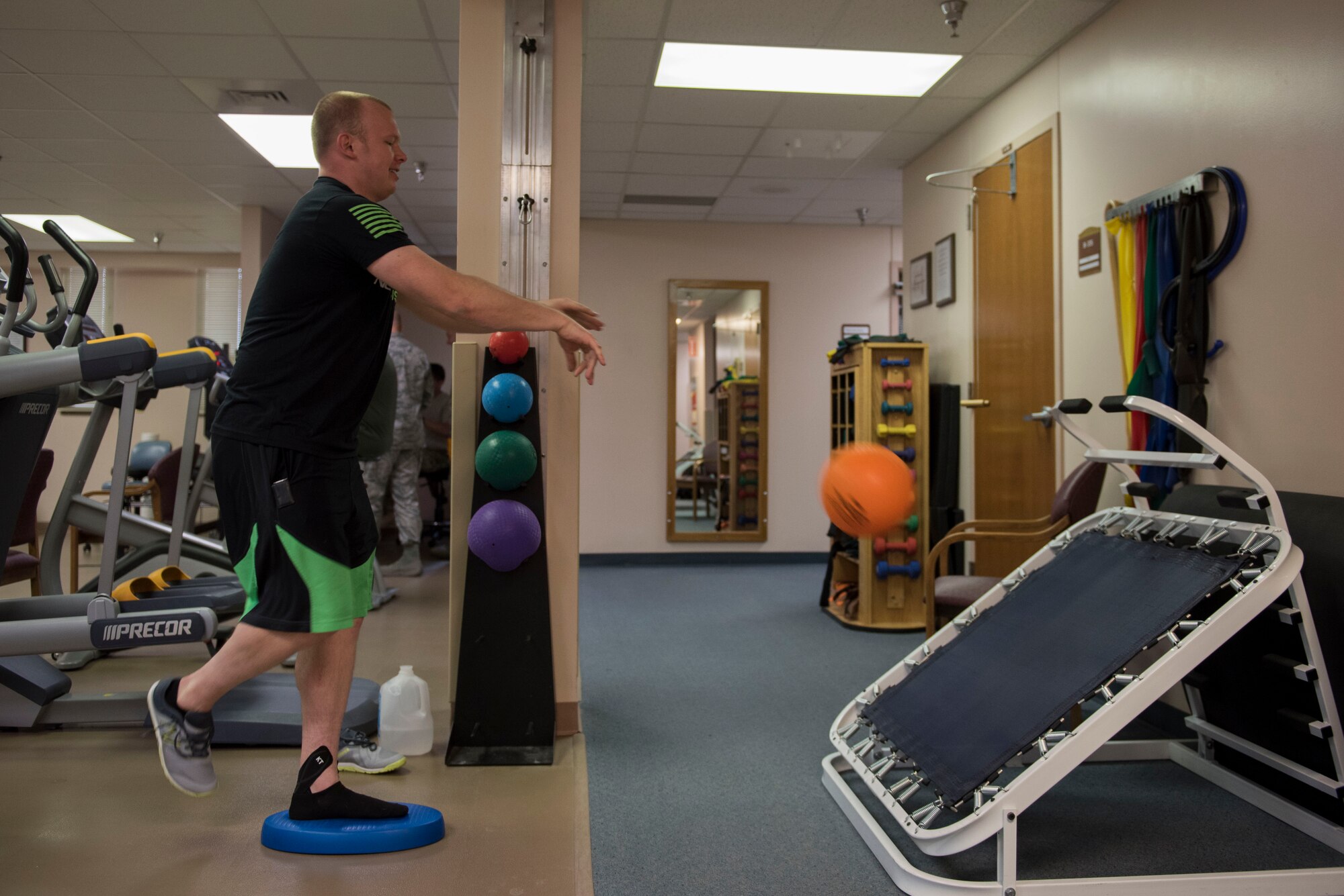 Casey Wheat, physical therapy patient, throws a medicine ball while balancing at the 27th Special Operations Medical Group Physical Medicine Office April 26, 2017, at Cannon Air Force Base, NM. On average, physical therapy sees 40 patients a day, most of which are repeat clients. Usually a patient will come in two or three times a week for one or two months. (U.S. Air Force photo by Staff Sgt. Michael Washburn/Released)