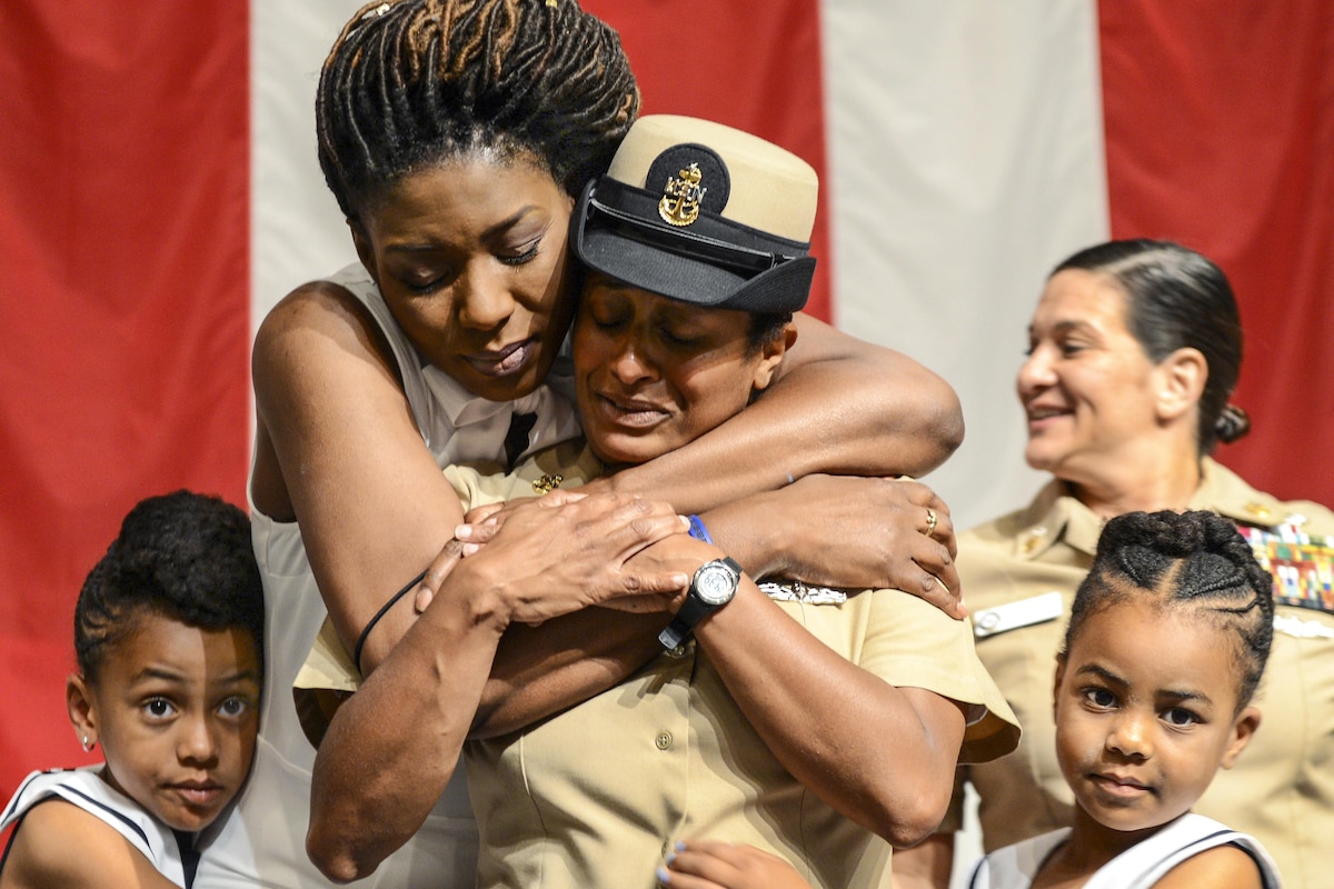 A sailor's family members embrace her after a ceremony.