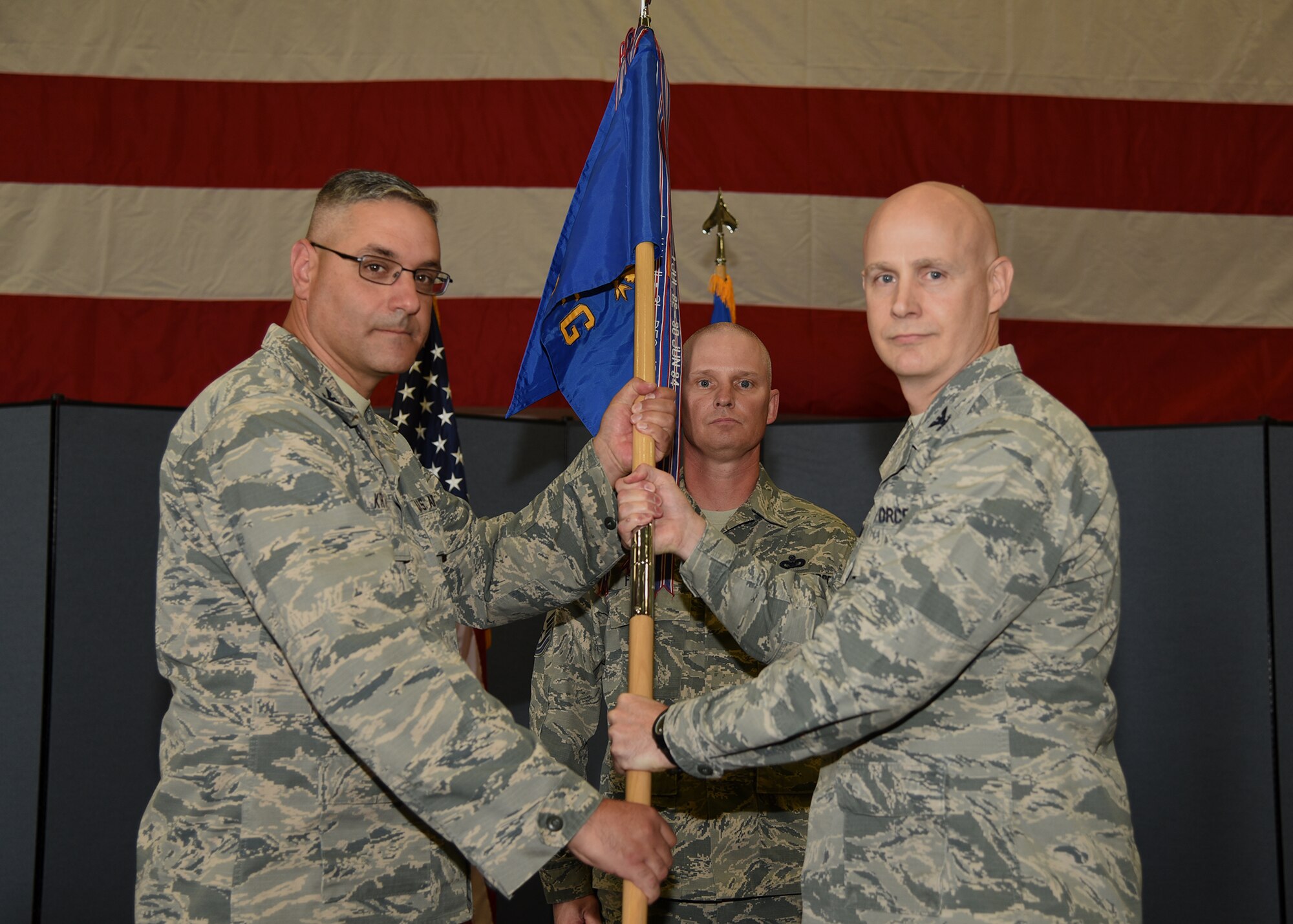 Colonel Stephen Kravitsky, 90th Missile Wing commander, passes the guidon to Col. John Grimm, 90th Security Forces Group commander, during the 90th SFG change of command ceremony June 9, 2017, as Chief Master Sgt. John Facemire, 90th SFG chief enlisted manager, stands in the background in the Peacekeeper High Bay on F.E. Warren Air Force Base, Wyo. The ceremony signified the transition of command from Col. Chris Corley to Grimm. (U.S. Air Force photo by Glenn S. Robertson)