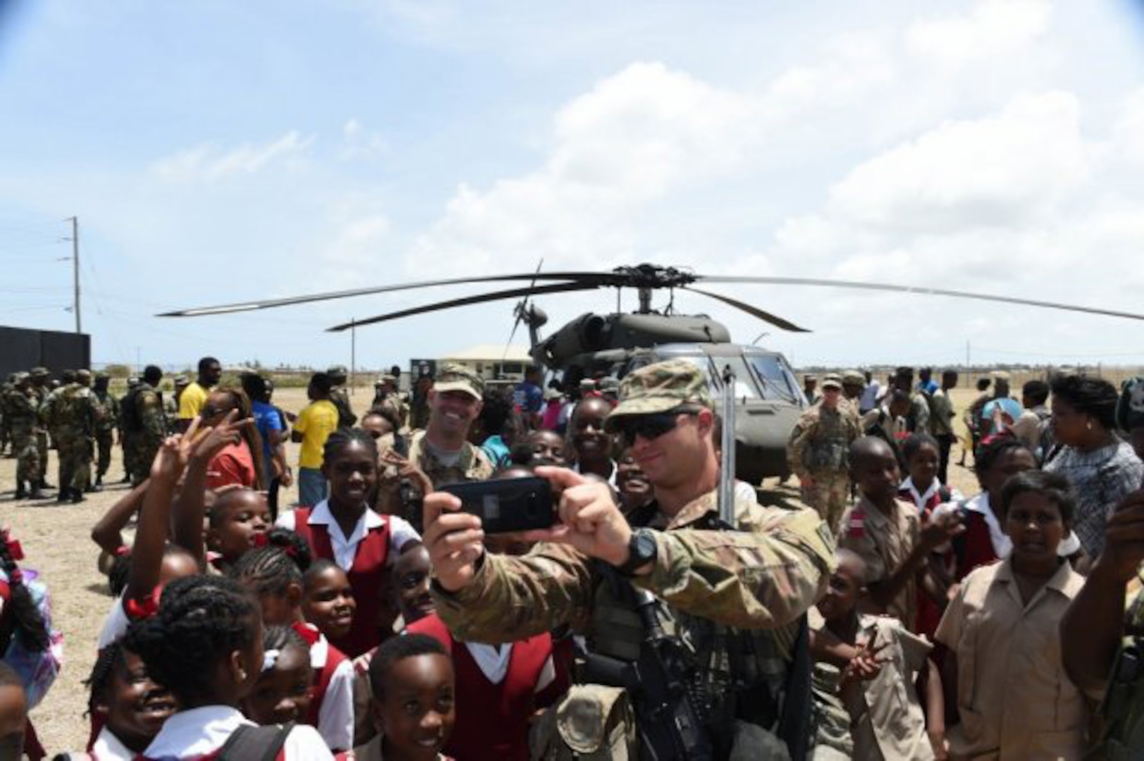 Florida Army National Guard 2nd lt. Ryan Noblitt, assigned to Delta Company, 1-124 Infantry, 53rd Brigade Combat Team, takes a selfie with schoolchildren and another Soldier in his unit, Staff Sgt. Edward Roseman during a community relations (COMREL) event on board Paragon Base. The students visited the base to participate in a Tradewinds 2017 COMREL event.