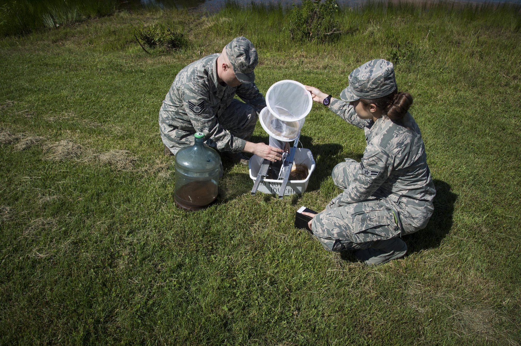 Staff Sgt. Nathan Higgins, 779th Medical Group public health technician, teaches Airman 1st Class Samantha Yordy, 779th MDG public health technician, how to set mosquito traps at the base lake on Joint Base Andrews, Md., June 8, 2017. Airmen from public health set traps about twice a week. (U.S. Air Force photo by Senior Airman Mariah Haddenham)