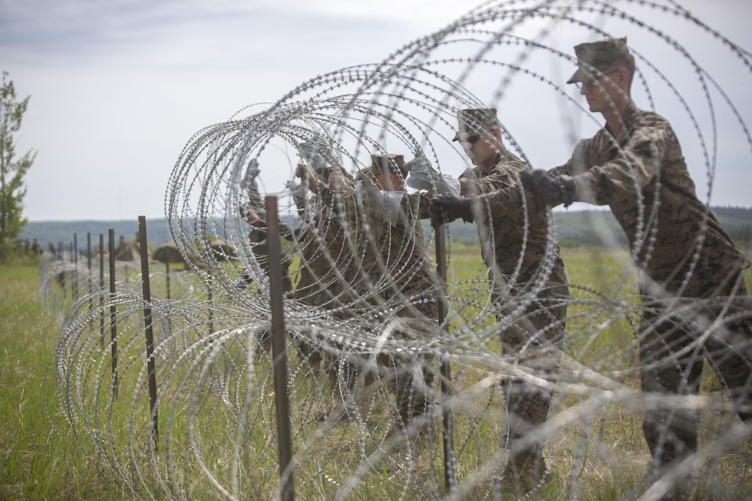 Combat Engineer Marines with Marine Wing Support Squadron 473, 4th Marine Aircraft Wing, Marine Forces Reserve, place a length of concertina wire to construct a triple standard concertina fence around their forward arming and refueling point at Canadian Forces Base Cold Lake during exercise Maple Flag 50, June 1, 2017. MWSS-473 is providing real world refueling support to Royal Canadian Air Force CH-147 Chinook and CH-146 Griffon type model series during exercise Maple Flag 50. (U.S. Marine Corps photo by Lance Cpl. Niles Lee/Released)