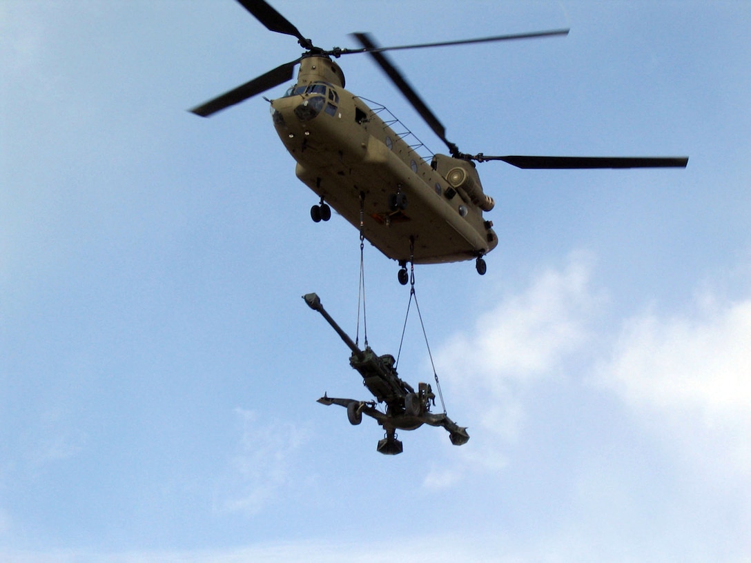 A CH-47 Chinook helicopter air lifts a M777 howiitzer to transport it to a forward operating base in a war zone. The pilots who lift the nearly five ton cannon train on inoperative M777 "lift guns" prepared for specifically that purpose at Production Plant Barstow, Marine Depot Maintenance Command, Marine Corps Logistics Base Barstow, Calif.