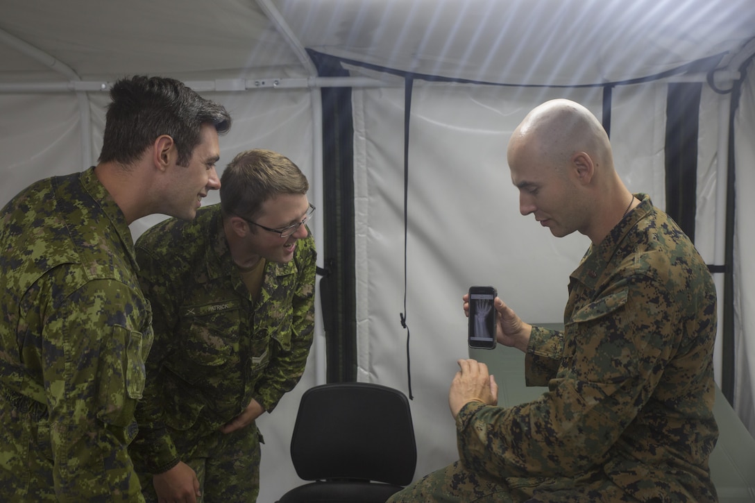 U.S. Navy Lt. Cmdr. Christian Basque, a navy doctor with Marine Wing Support Squadron 472, Marine Aircraft Group 49, 4th Marine Aircraft Wing, Marine Forces Reserve, shows pictures of X-rays from his civilian job as a sports medicine physician to Canadian medical technicians during exercise Maple Flag 50 at Canadian Forces Base Cold Lake, Alberta, June 2, 2017. Maple Flag is an annual multi-national training exercise hosted by the Royal Canadian Air Force with foreign nations training together to complete simulated combat missions. (U.S. Marine Corps photo by Lance Cpl. Niles Lee/Released)