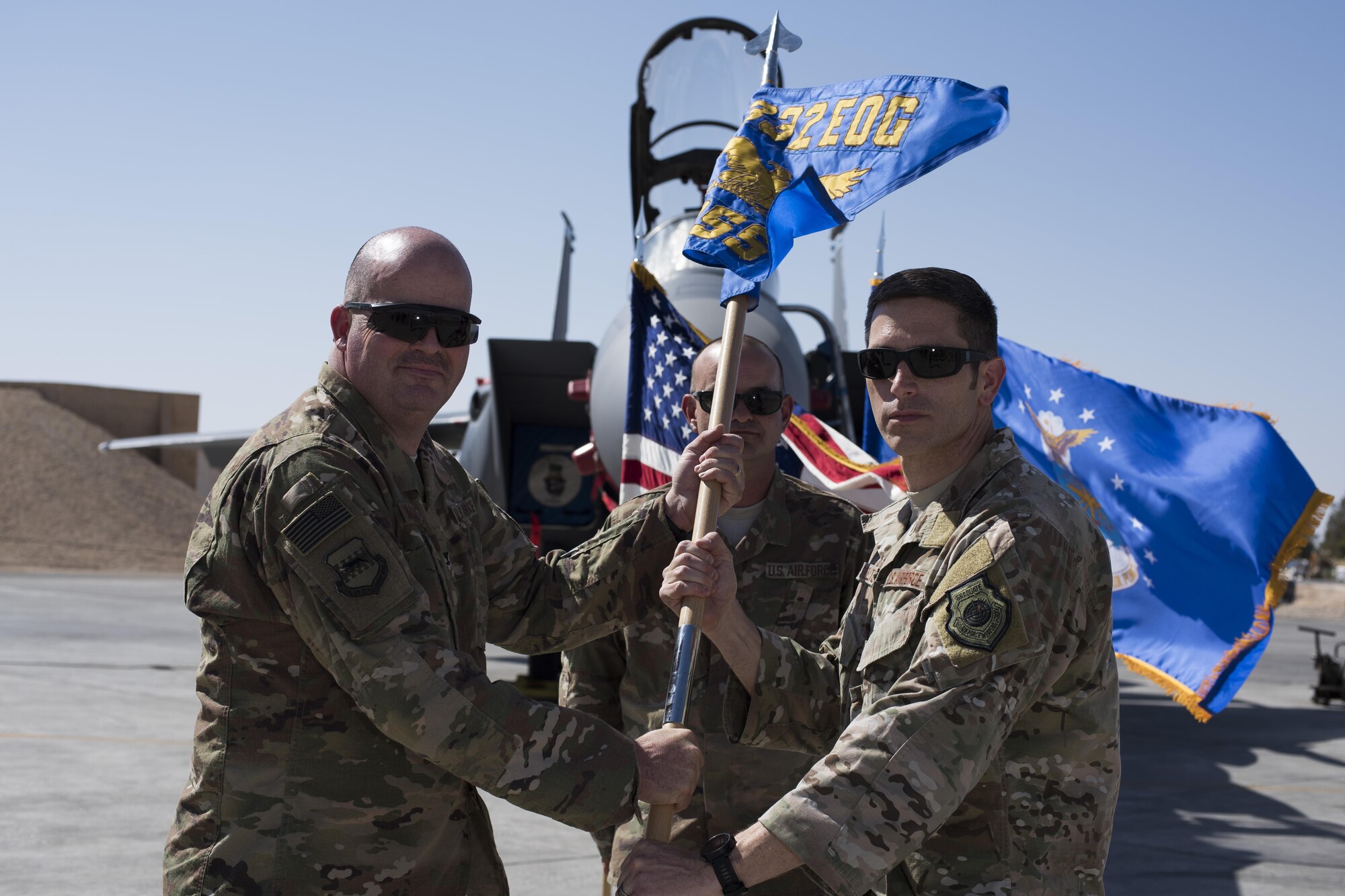 Col. William L. Marshall, 332nd Expeditionary Operations Group commander, left, passes the guidon to Lt. Col. Nathan G. Shelton, during the 332nd Expeditionary Operations Support Squadron assumption of command ceremony June 8, 2017, in Southwest Asia. The passing of a guidon symbolizes a unit’s transfer of command. (U.S. Air Force photo/Senior Airman Damon Kasberg)