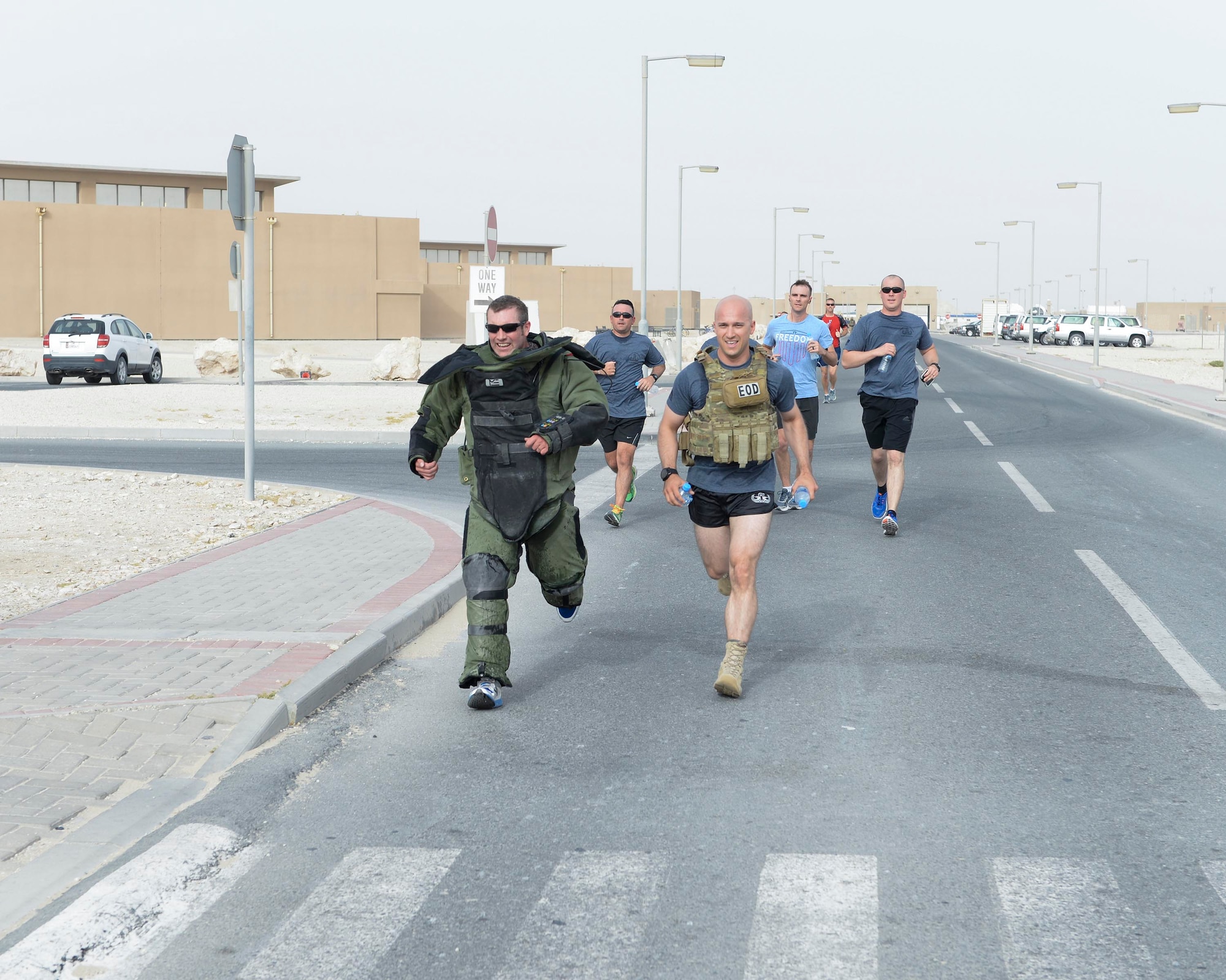 U.S. Air Force Staff Sgts. Brent Points, left, in the bomb suit, and Andrew Vitale, right front, explosive ordinance technicians assigned to the 379th Civil Engineering Squadron, push through the finish together, completing the annual EOD 5K Memorial Run at Al Udeid Air Base, Qatar, June 3, 2017. Points and Vitale joined service members from across the base who gathered to take part in the EOD 5K Memorial Run in memory of the EOD men and women killed in action during combat operations. (U.S. Air Force photo by Tech. Sgt. Bradly A. Schneider/Released)
