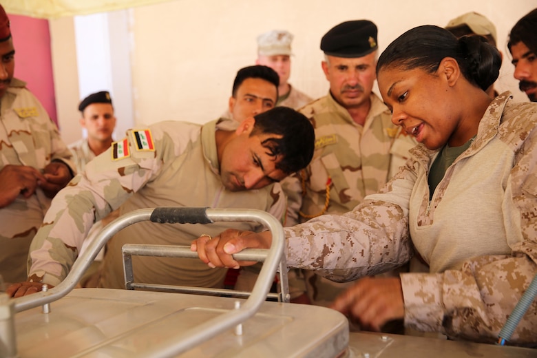 U.S. Marine Corps Staff Sgt. Shakelia Woods, a food service specialist with Special Purpose Marine Air-Ground Task Force-Crisis Response-Central Command, gives instruction on an Ozti Field Kitchen (OFK) to Iraqi soldiers with the 7th Iraqi Army Division during an Advise and Assist mission in support of Task Force Al Asad in Iraq May 4, 2017. Task Force Al Asad trains Iraqi forces with operationally relevant training, an integral aspect of Combined Joint Task Force-Operation Inherent Resolve, the global coalition to defeat ISIS in Iraq and Syria.(U.S. Marine Corps photo by Staff Sgt. Jennifer B. Poole)