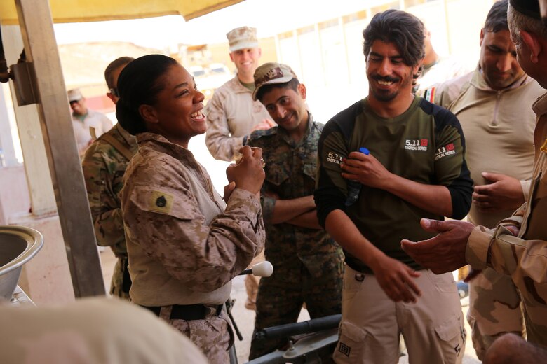 U.S. Marine Corps Staff Sgt. Shakelia Woods, a food service specialist with Special Purpose Marine Air-Ground Task Force-Crisis Response-Central Command, shares a laugh with Iraqi soldiers with the 7th Iraqi Army Division during an advise and assist mission in support of Task Force Al Asad in Iraq May 4, 2017. Task Force Al Asad trains Iraqi forces with operationally relevant training, an integral aspect of Combined Joint Task Force-Operation Inherent Resolve, the global coalition to defeat ISIS in Iraq and Syria.(U.S. Marine Corps photo by Staff Sgt. Jennifer B. Poole) 