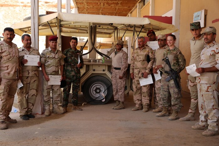 U.S. Marine Corps Staff Sgt. Shakelia Woods, a food service specialist with Special Purpose Marine Air-Ground Task Force-Crisis Response-Central Command, and Iraqi soldiers with the 7th Iraqi Army Division pose in front of an Ozti Field Kitchen (OFK) after completing a week-long instruction in Iraq May 4, 2017. Task Force Al Asad trains Iraqi forces with operationally relevant training, an integral aspect of Combined Joint Task Force-Operation Inherent Resolve, the global coalition to defeat ISIS in Iraq and Syria.. (U.S. Marine Corps photo by Staff Sgt. Jennifer B. Poole) 