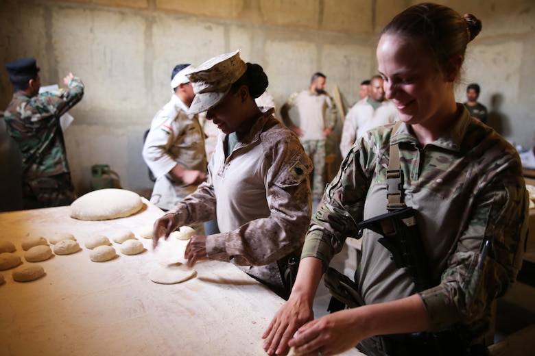 U.S. Marine Corps Staff Sgt. Shakelia Woods, a food service specialist with Special Purpose Marine Air-Ground Task Force-Crisis Response-Central Command, and Sgt. Susan Molinar, a culinary noncommissioned officer with the 314th Combat Support Sustainment Battalion, roll dough to make khubuz, a traditional Iraqi flat bread at Al Asad Air Base, Iraq, May 4, 2017. Woods instructed Iraqi soldiers with the 7th Iraqi Army Division on capabilities and employment of an Ozti Field Kitchen (OFK) during an advise and assist mission in support of Task Force Al Asad. Task Force Al Asad trains Iraqi forces with operationally relevant training, an integral aspect of Combined Joint Task Force-Operation Inherent Resolve, the global coalition to defeat ISIS in Iraq and Syria.(U.S. Marine Corps photo by Staff Sgt. Jennifer B. Poole) 