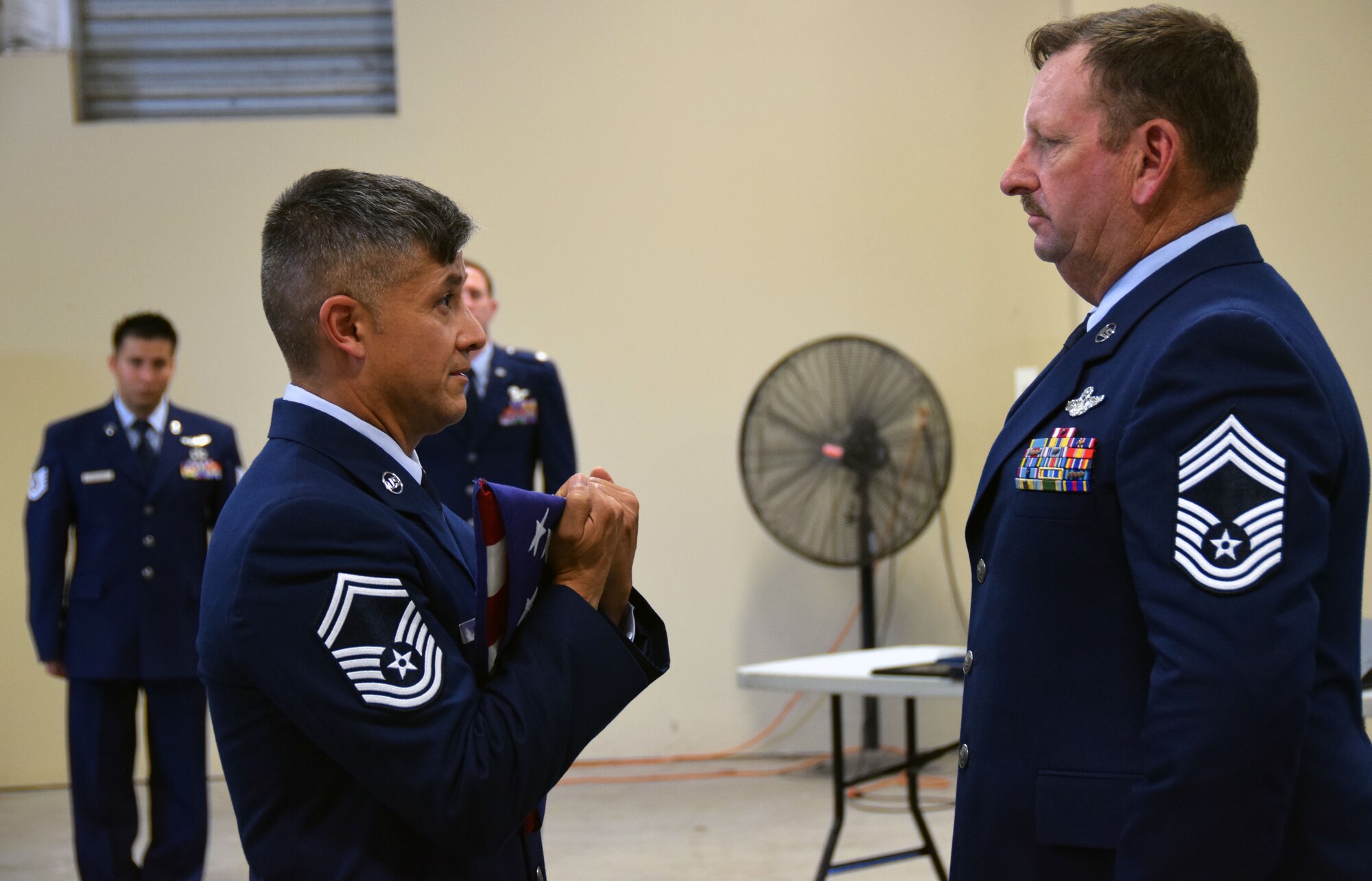 Senior Master Sgt. Miguel Casso, 356th Airlift Squadron loadmaster instructor, presents a United States flag to Chief Master Sgt. Thomas J. Veilleux Sr., 356th Airlift Squadron’s Formal Training Unit superintendent, during the chief’s retirement ceremony at the Cargo Loading Training Facility at Joint Base San Antonio-Lackland, Texas June 11, 2017.  The chief’s career, which spanned over 34 years, began in  August 1979 in Security Forces as a dog handler. (U.S. Air Force photo by Tech. Sgt. Carlos J. Trevino)