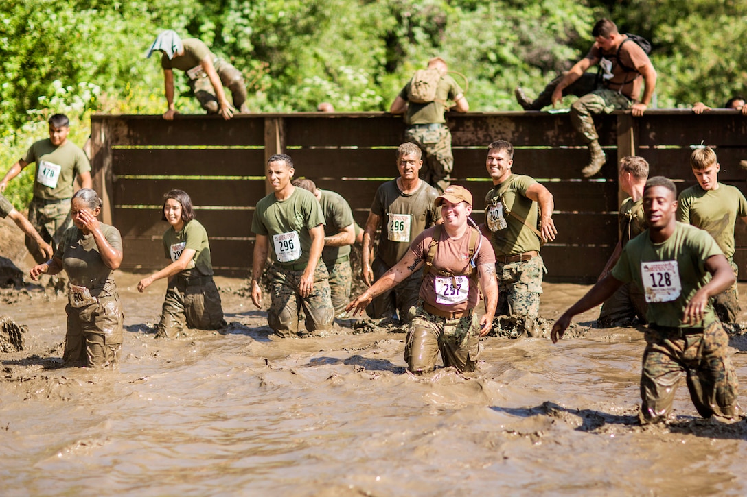 Marines and sailors climb over a mud wall while participating in the 2017 Marine Corps Mud Run by Lake O'Neill at Camp Pendleton, Calif, June 9, 2017. Marine Corps photo by Sgt. Hector de Jesus