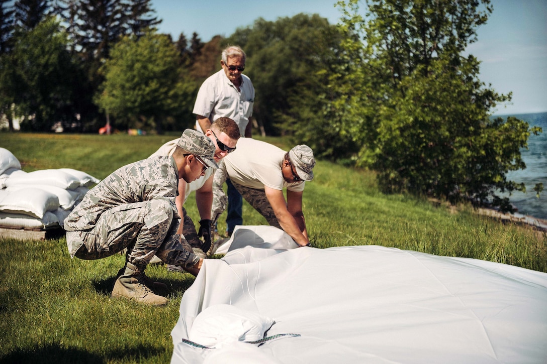 New York Air National Guard airmen secure a plastic sheet with sandbags to divert waves from Lake Ontario impacting onto a local home owner’s property, Wilson, N.Y., June 9, 2017. Air National Guard photo by Staff Sgt. Ryan Campbell