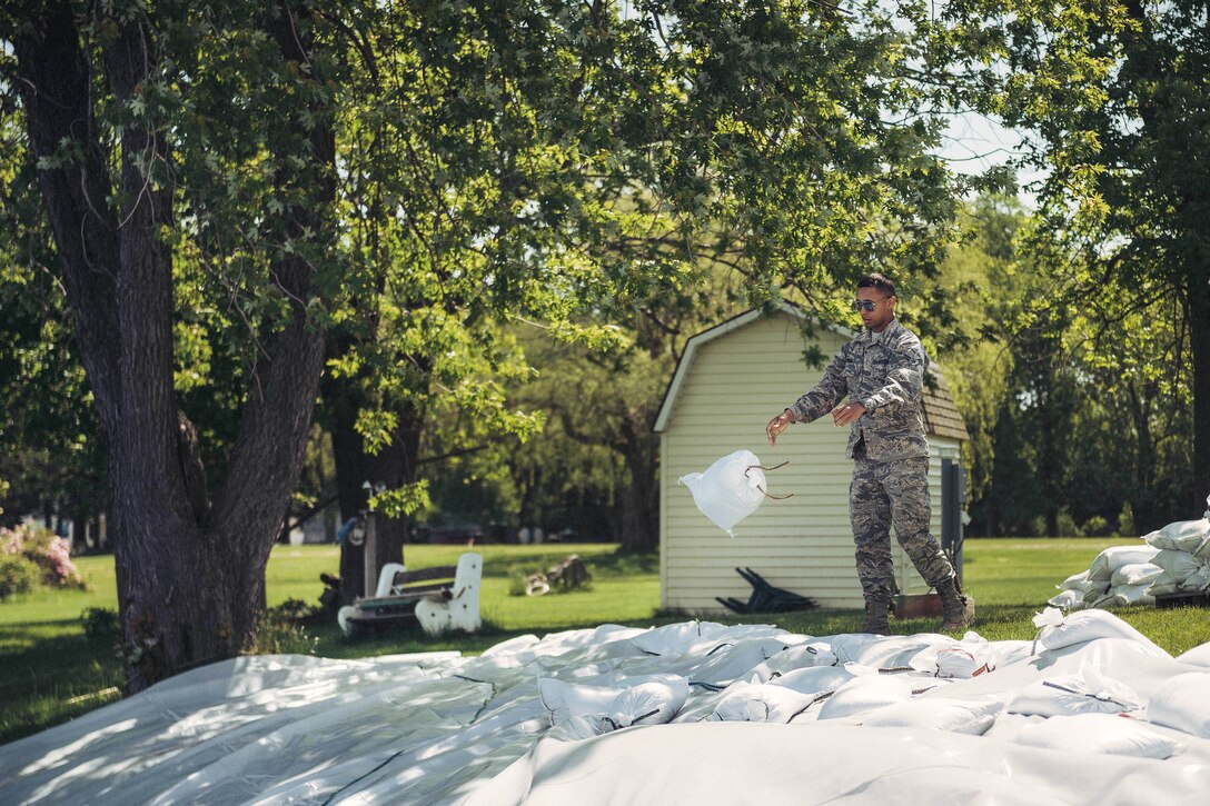 A New York Air National Guard airman tosses sandbags onto a plastic sheet to divert waves from Lake Ontario impacting onto a local home owner’s property, Wilson, N.Y., June 9, 2017. Air National Guard photo by Staff Sgt. Ryan Campbell