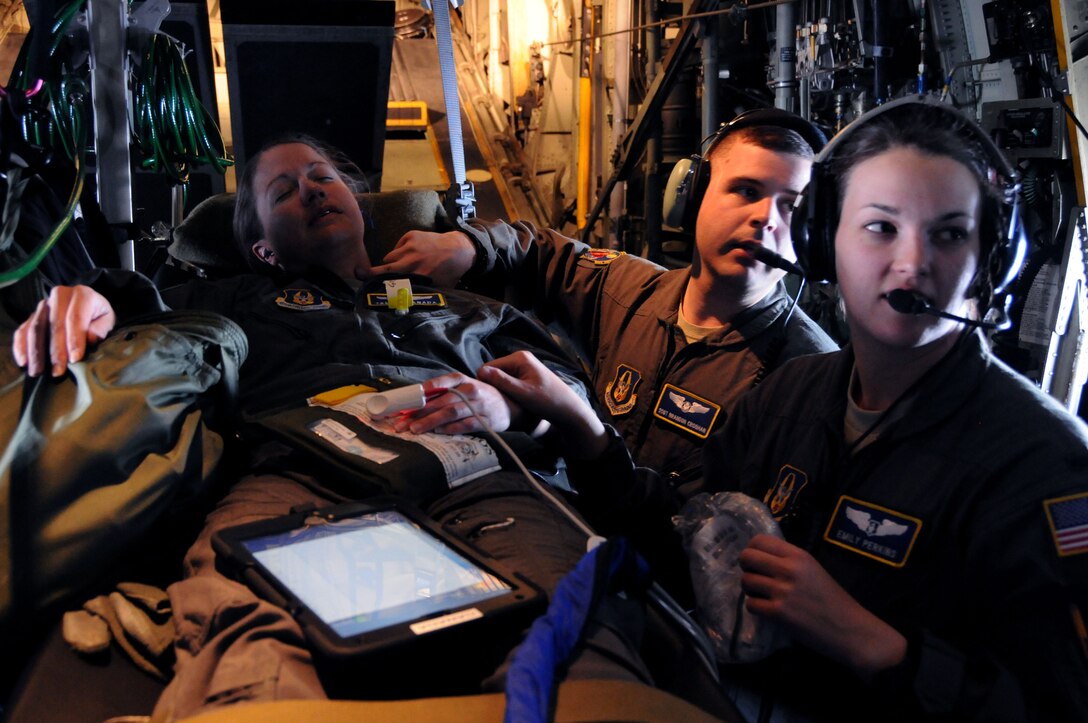 445th Aeromedical Evacuation Squadron crew members, 1st Lt. Emily Perkins and Staff Sgt. Brandon Croghan, check the pulse of a Citizen Airman portraying a patient for a joint training mission here, June 7 2017. The 445th AES trained for two hours while airborne to simulate a real-world scenario. (U.S. Air Force photo/Senior Airman Joshua Kincaid)